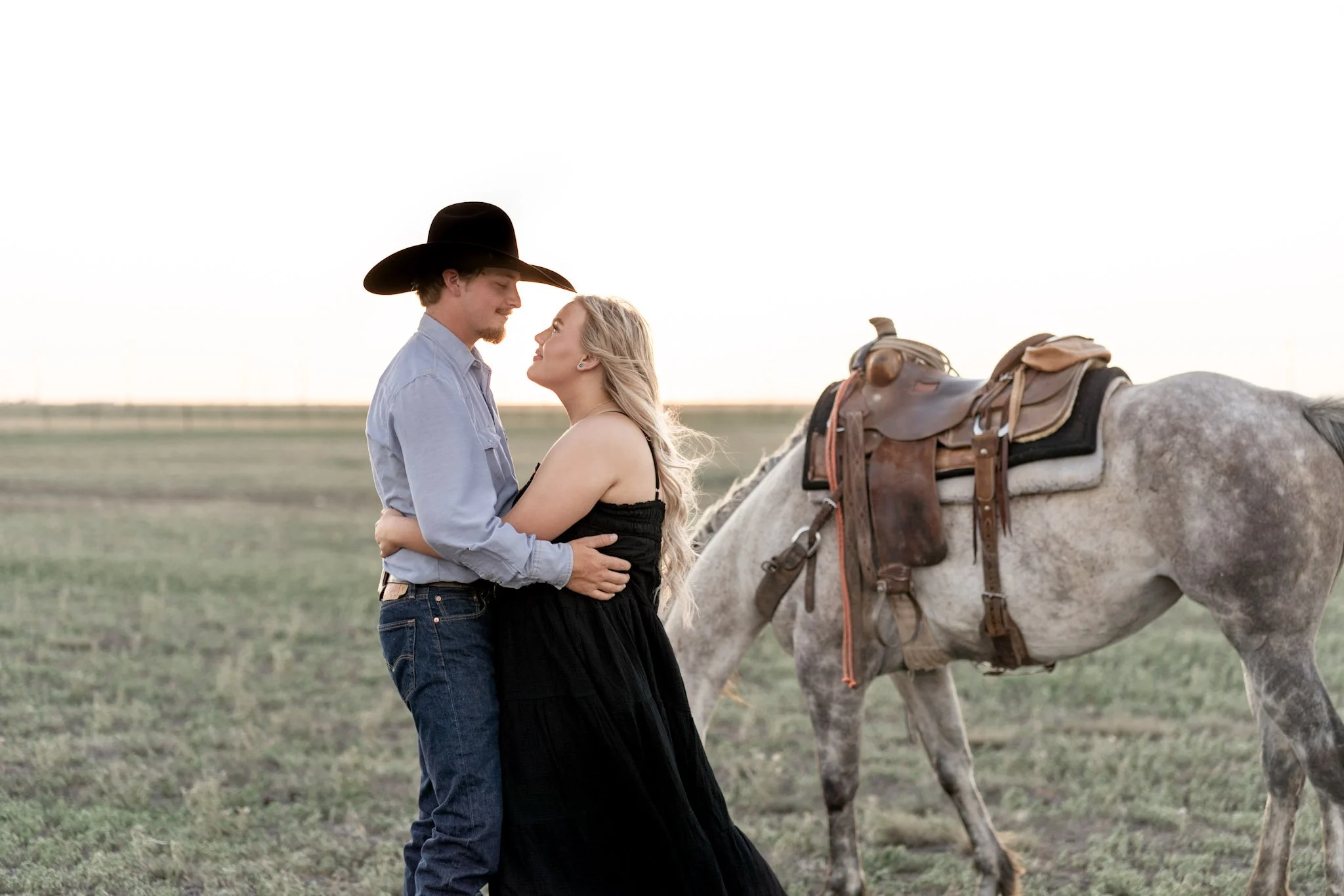 a western couple embracing in front of a texas panhandle sky and horse