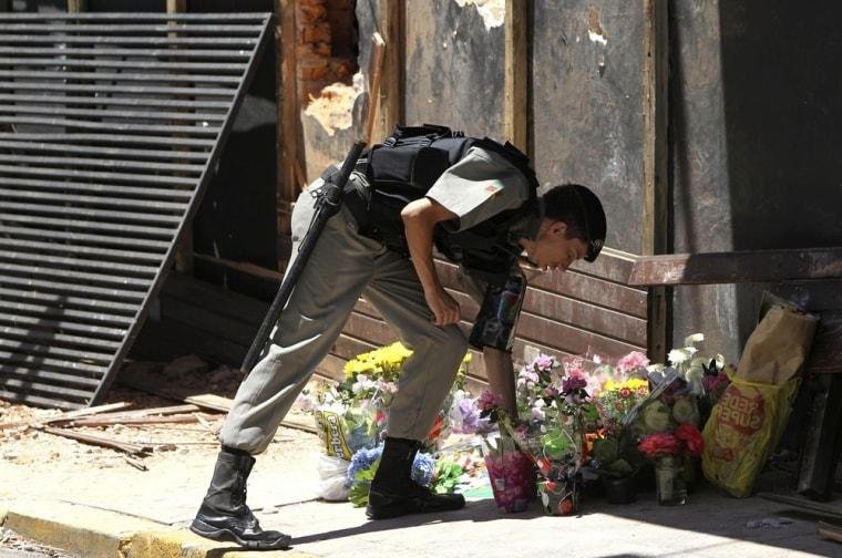  Police officer leaving flowers in front of Kiss nightclub after the incident 