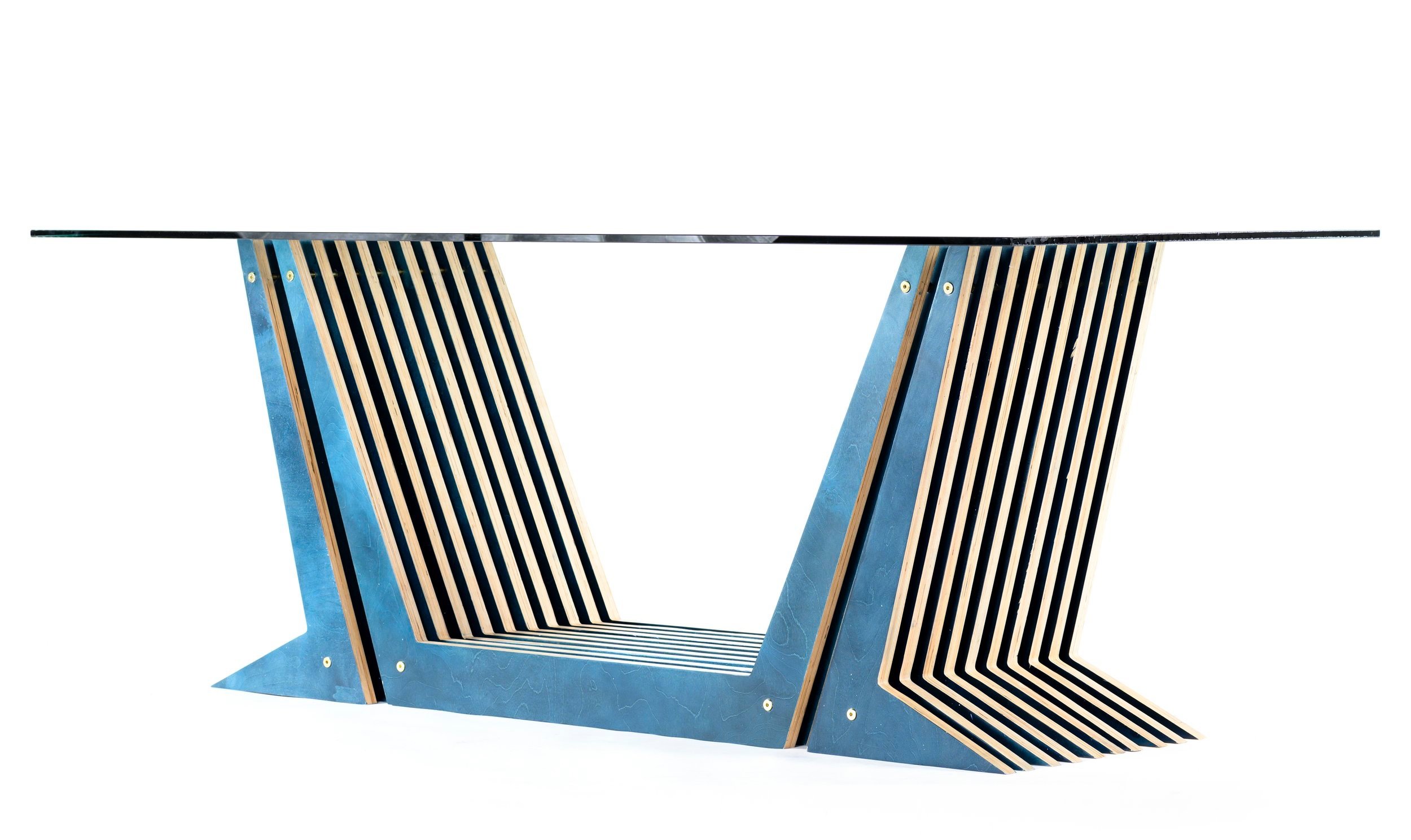 Modern architectural desk with a tempered glass top surface and geometric blue finish wooden slats supporting it, set against a white background.