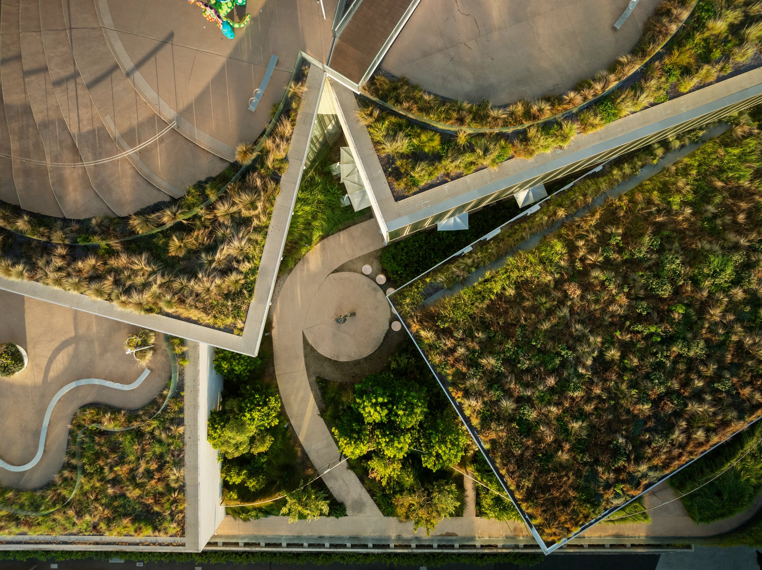 An aerial view of a modern building with roof gardens, outdoor seating areas, and landscaped greenery. Designed by McGregor Coxall Photo by Ruth Gold