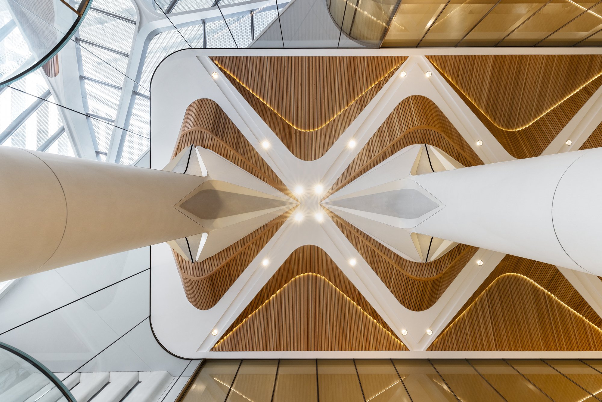 View looking up at modern interior architecture with wooden panels and white structural elements. Designed by fjcStudio Photo by Ruth Gold