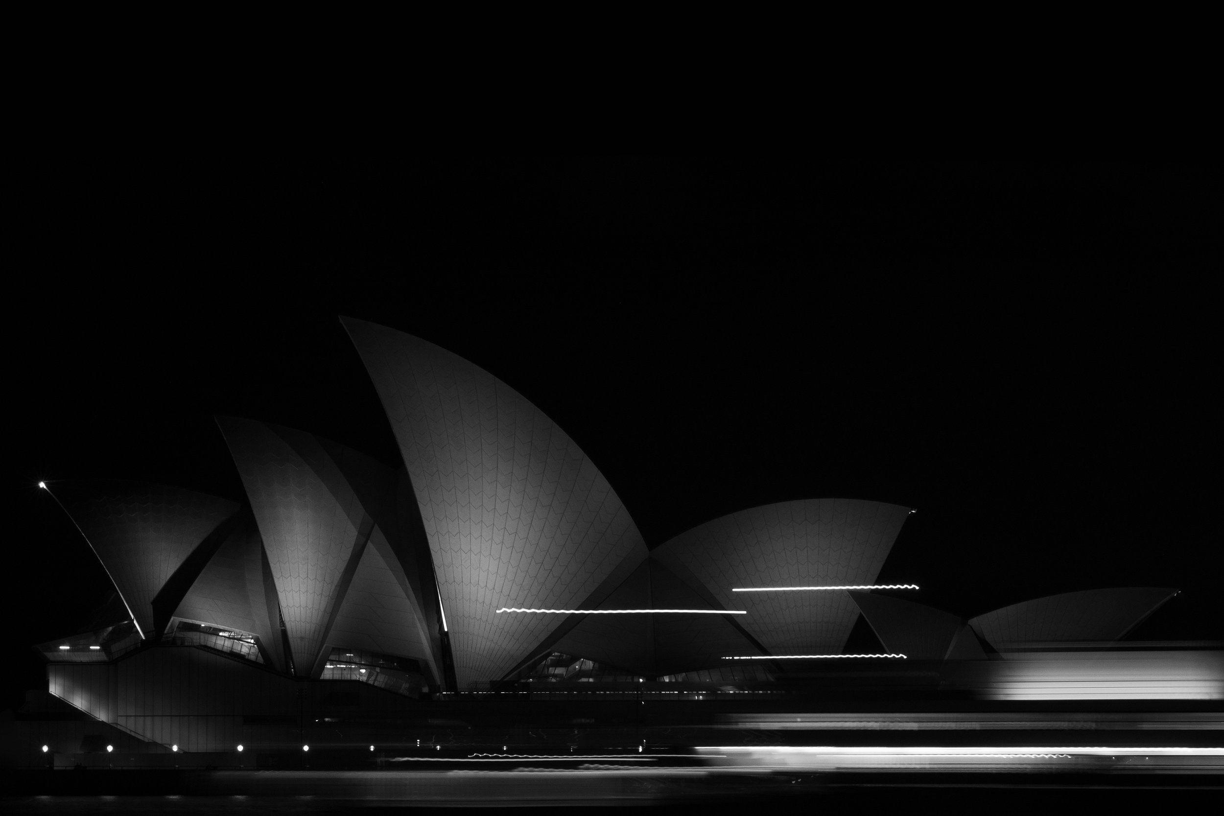 Night view of the Sydney Opera House with light trails from passing vehicles. Opera House Photo by Ruth Gold