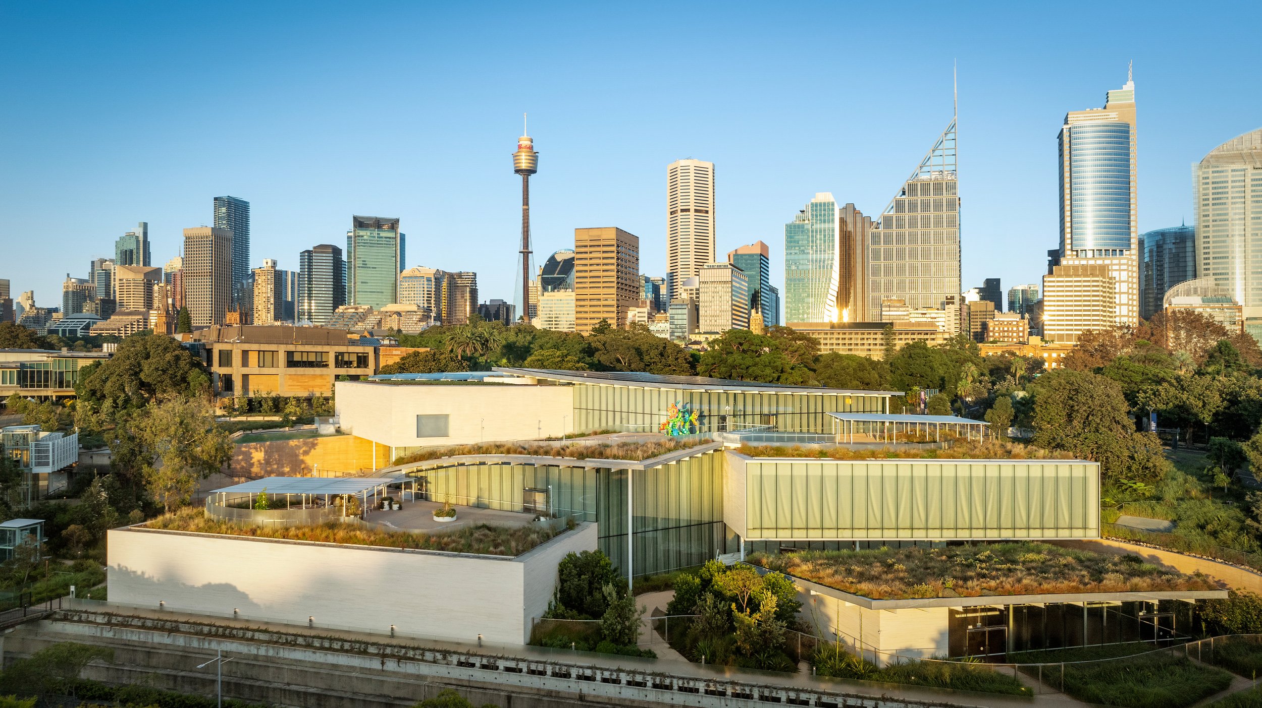 City skyline with modern skyscrapers and a contemporary building with greenery in the foreground. Designed by McGregor Coxall Photo by Ruth Gold