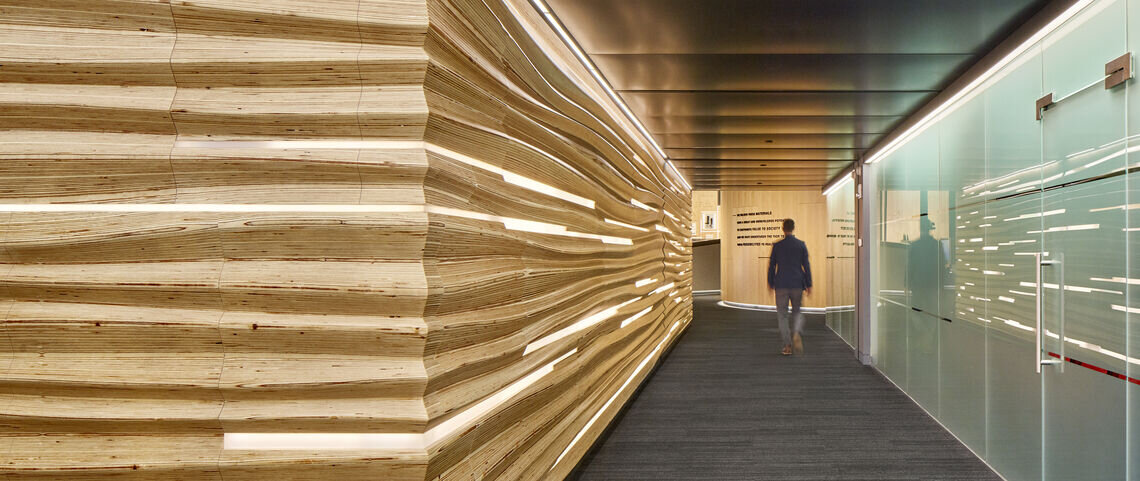A man walks down a hallway with intricate wood cuts.