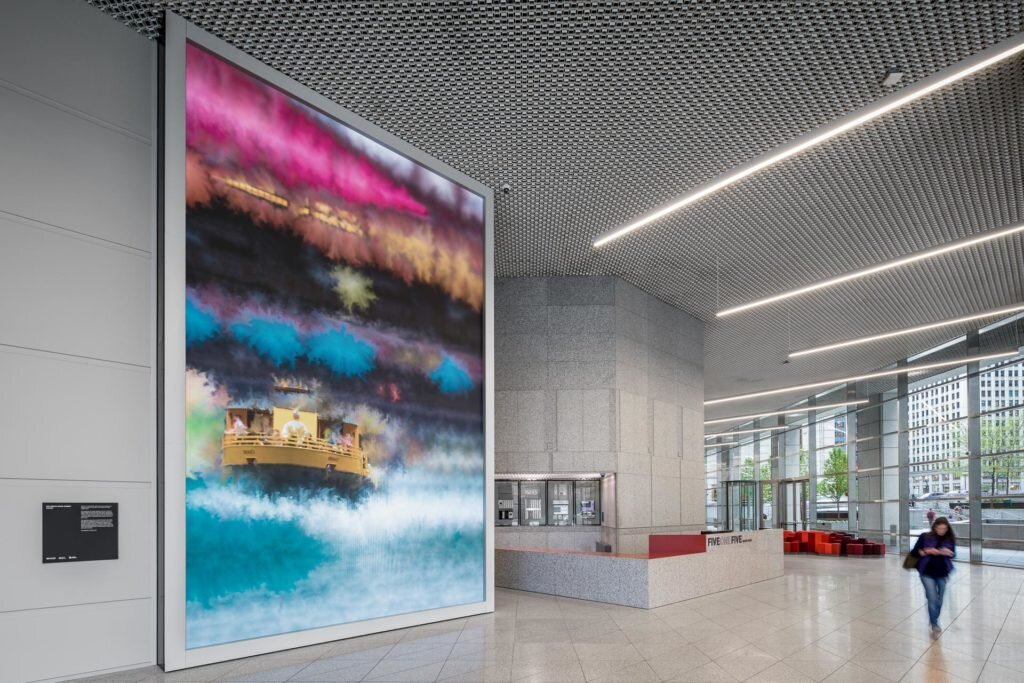 A vibrant light board displays colorful abstract art as a woman walks through the lobby.