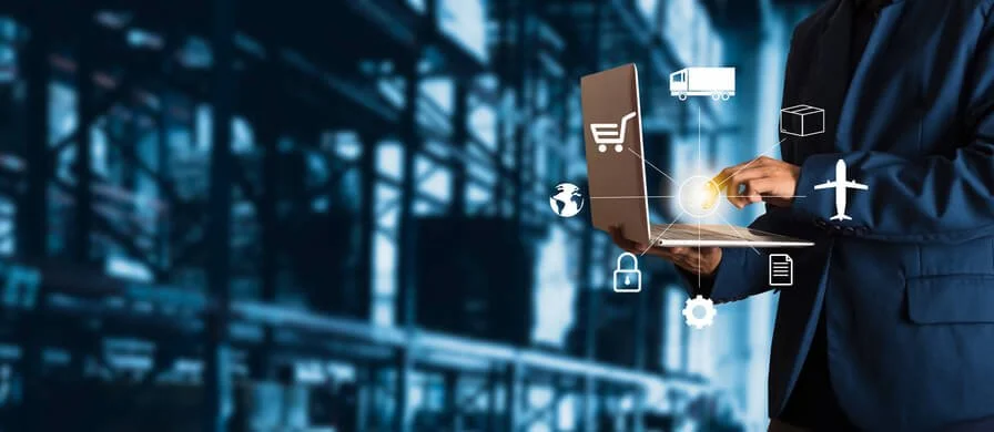 IT professional using laptop inventory management and device tracking software in a warehouse environment to manage laptop deployments, shipping, and IT asset visibility