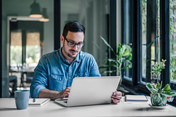 Remote employee sitting in front of a laptop, representing laptop tracking and return process for IT asset management