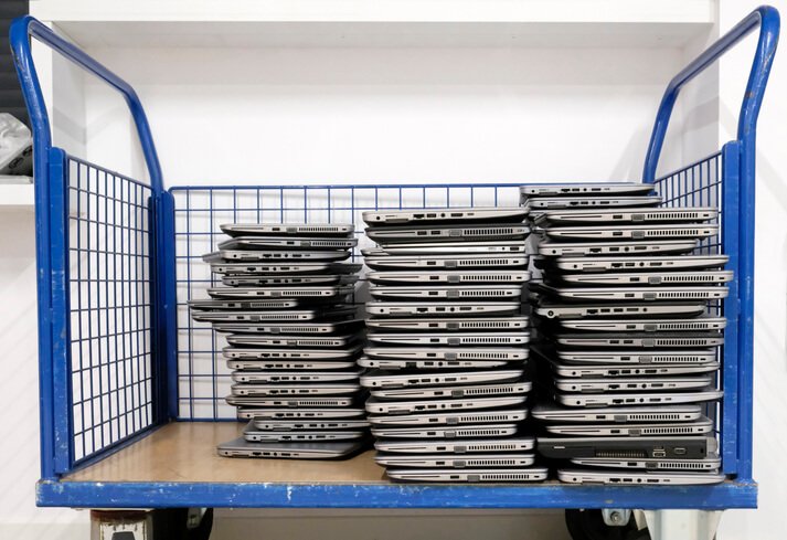Stacks of returned company laptops stored securely in a controlled warehouse environment.