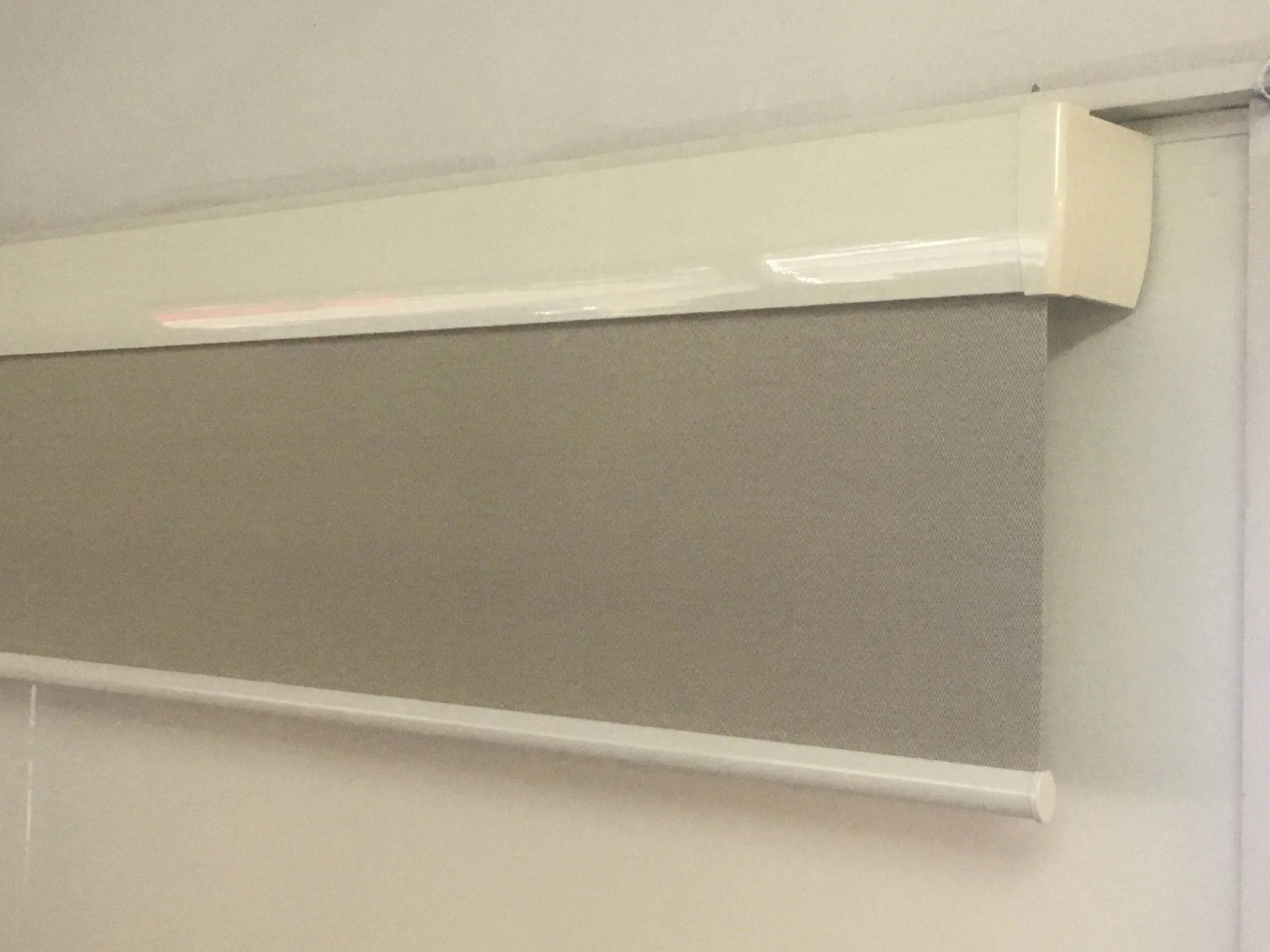 A white AC air conditioning unit mounted high on a gray wall.