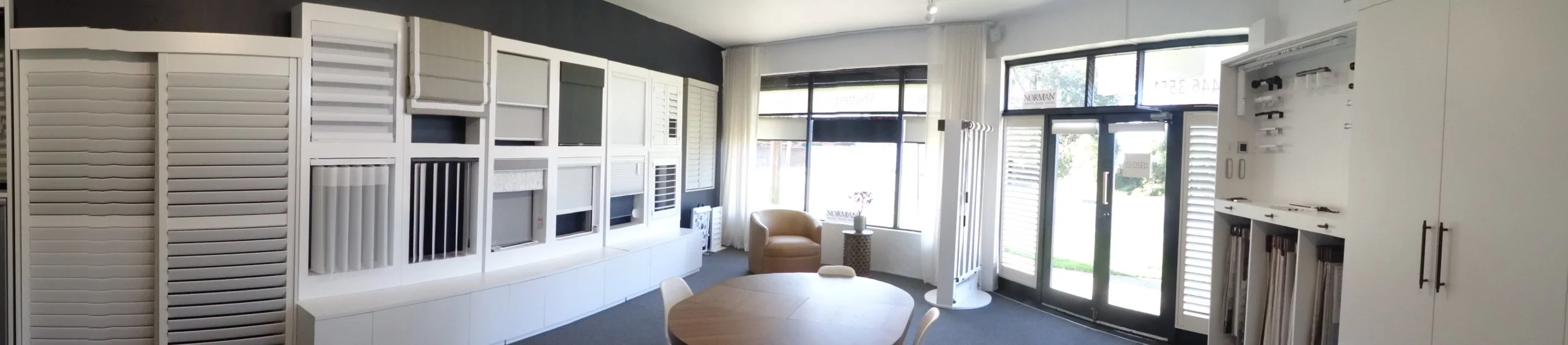 Showroom displaying window shutters, blinds, and window treatment options in a bright, modern space.