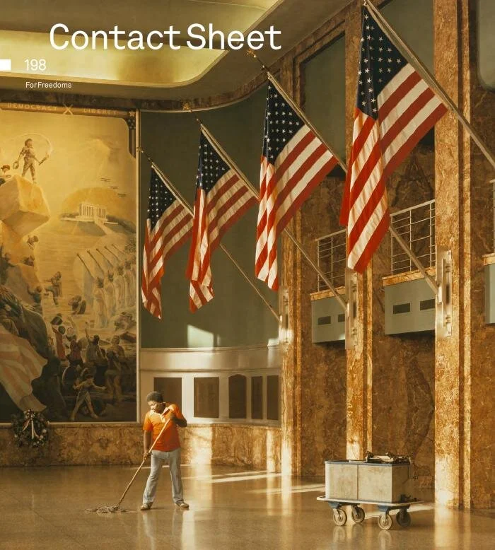 A person mopping the floor in an interior with American flags hanging from the ceiling and a mural in the background.