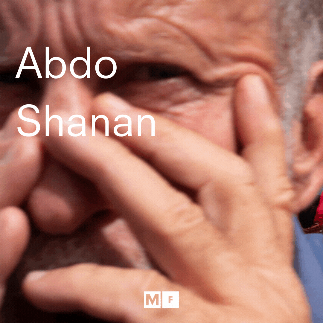 Close-up of an elderly person's face with their hand partially covering it, with text overlay that reads 'Abdo Shanan'.