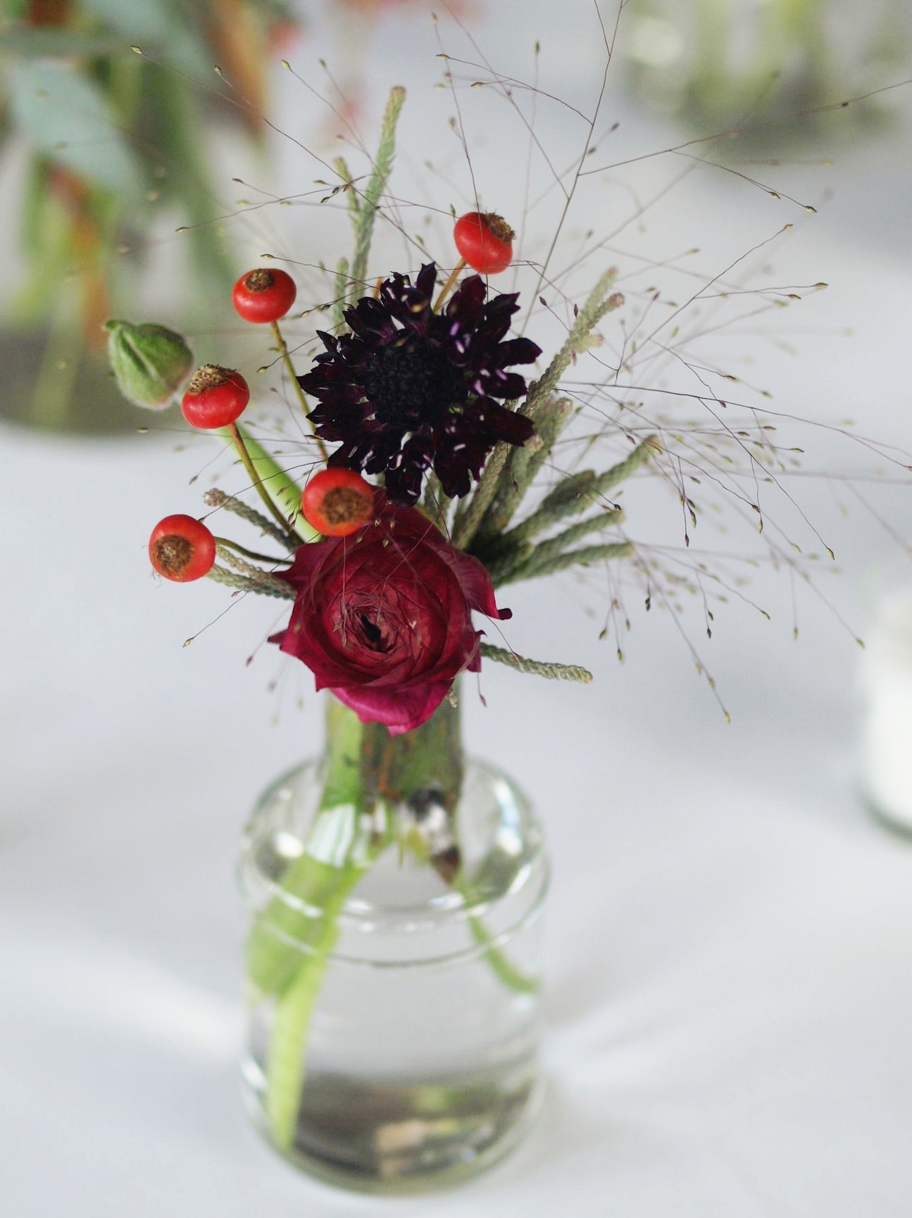 Oreonta house woodstock wedding bud vase with burgundy ranunculous, , grey brunia, red berries and red rosehips and wildflowers rosehip social rosehip floral wild grass.jpg