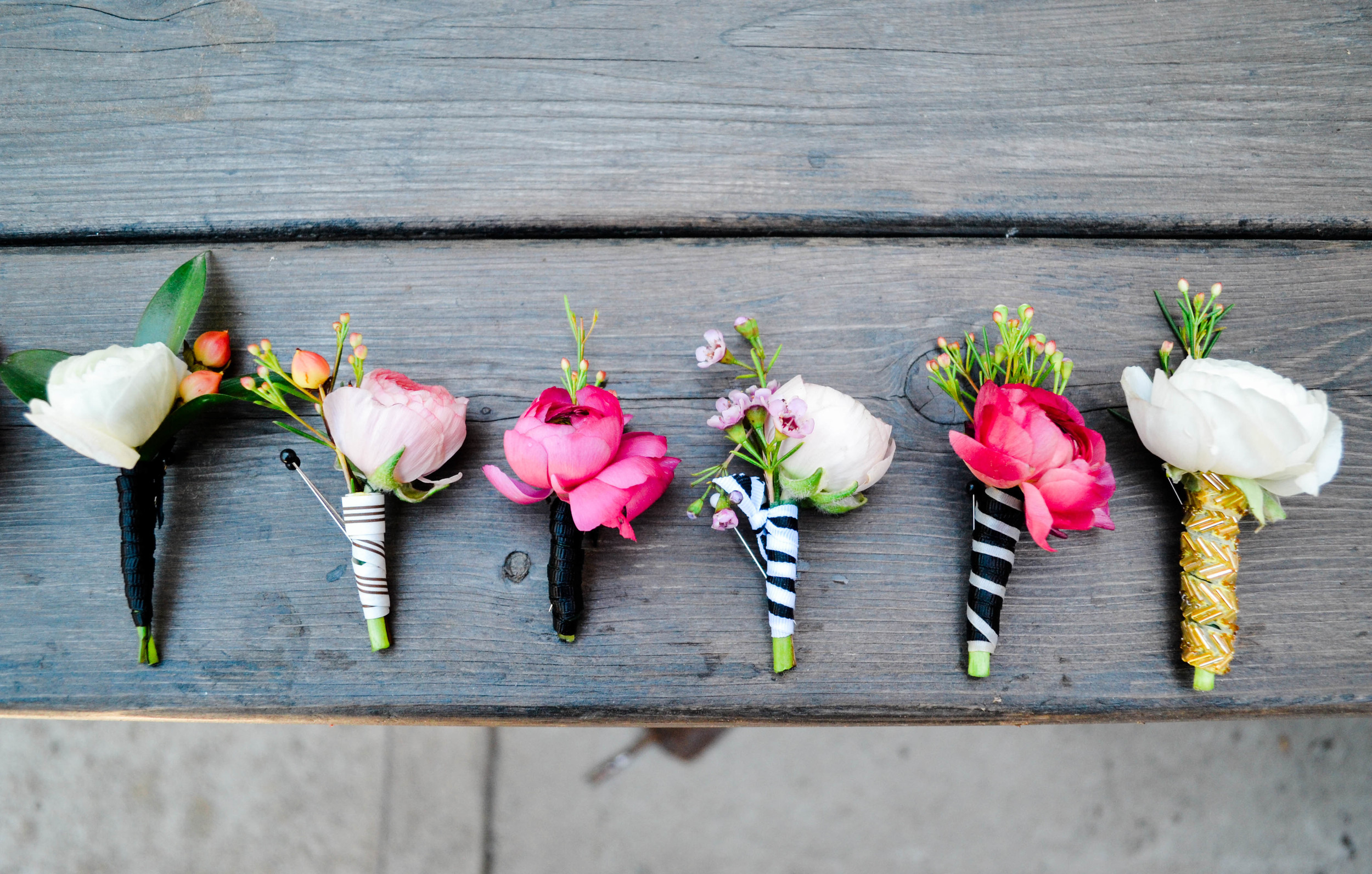 Pink, white, and red boutineers with mismatched black, gold, and navy blue striped ribbons!  Rosehip Social, Brooklyn, NY.