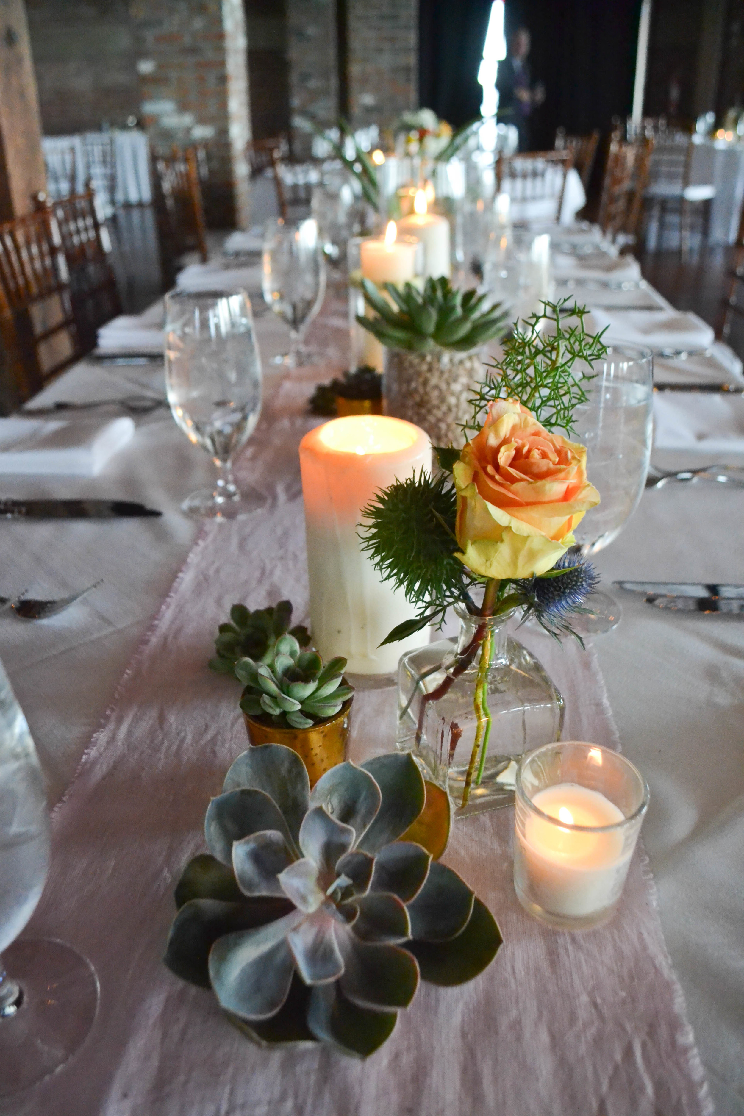 Liberty Warehouse Southwest Succulent Mexican wedding. Rosehip Floral BrooklynOrange, pink, white and slate blue centerpieces with succulents and candles.