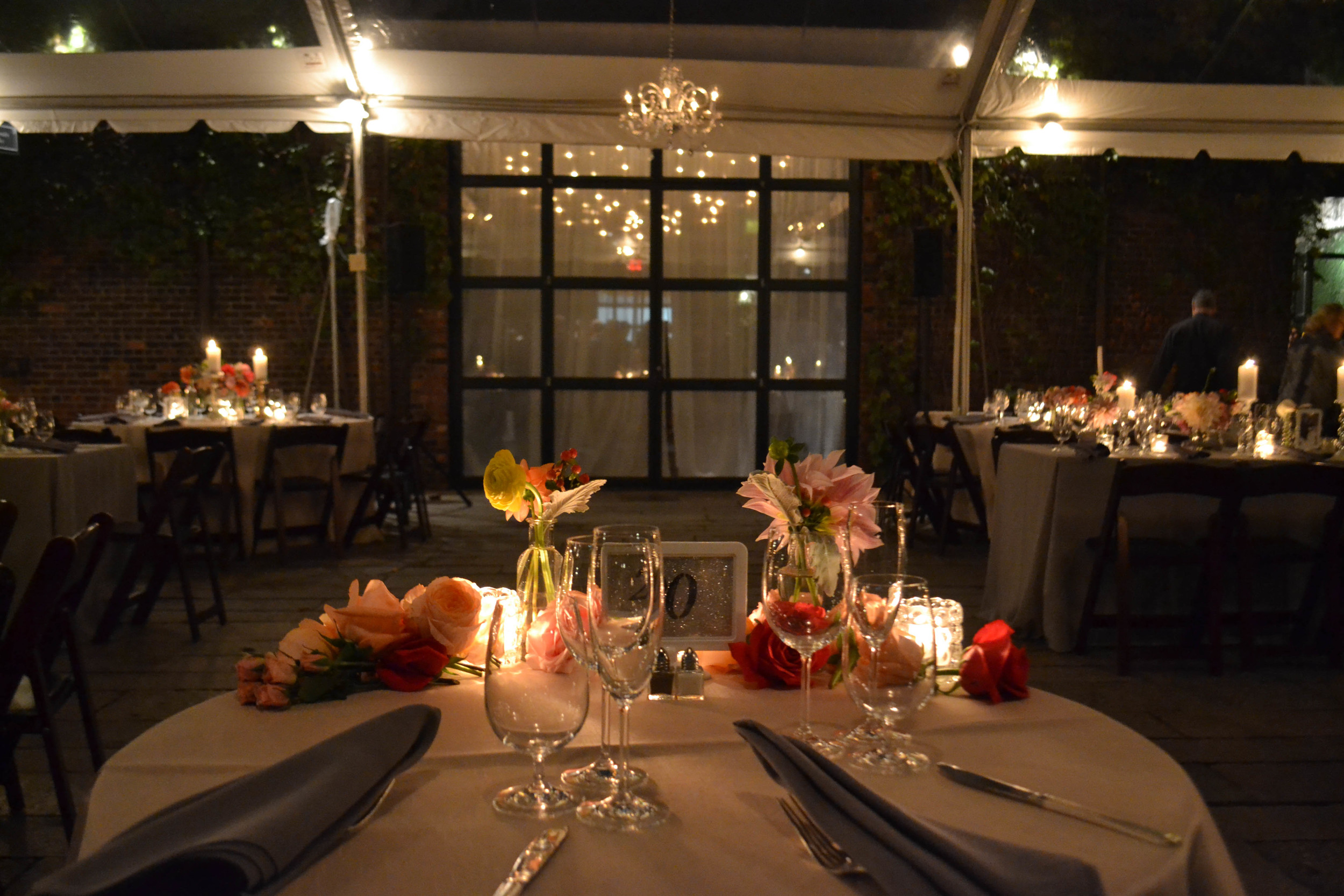 Candlelit centerpieces with pillar candles and pink and peach toned flowers. Foundry LIC. Rosehip Social. 