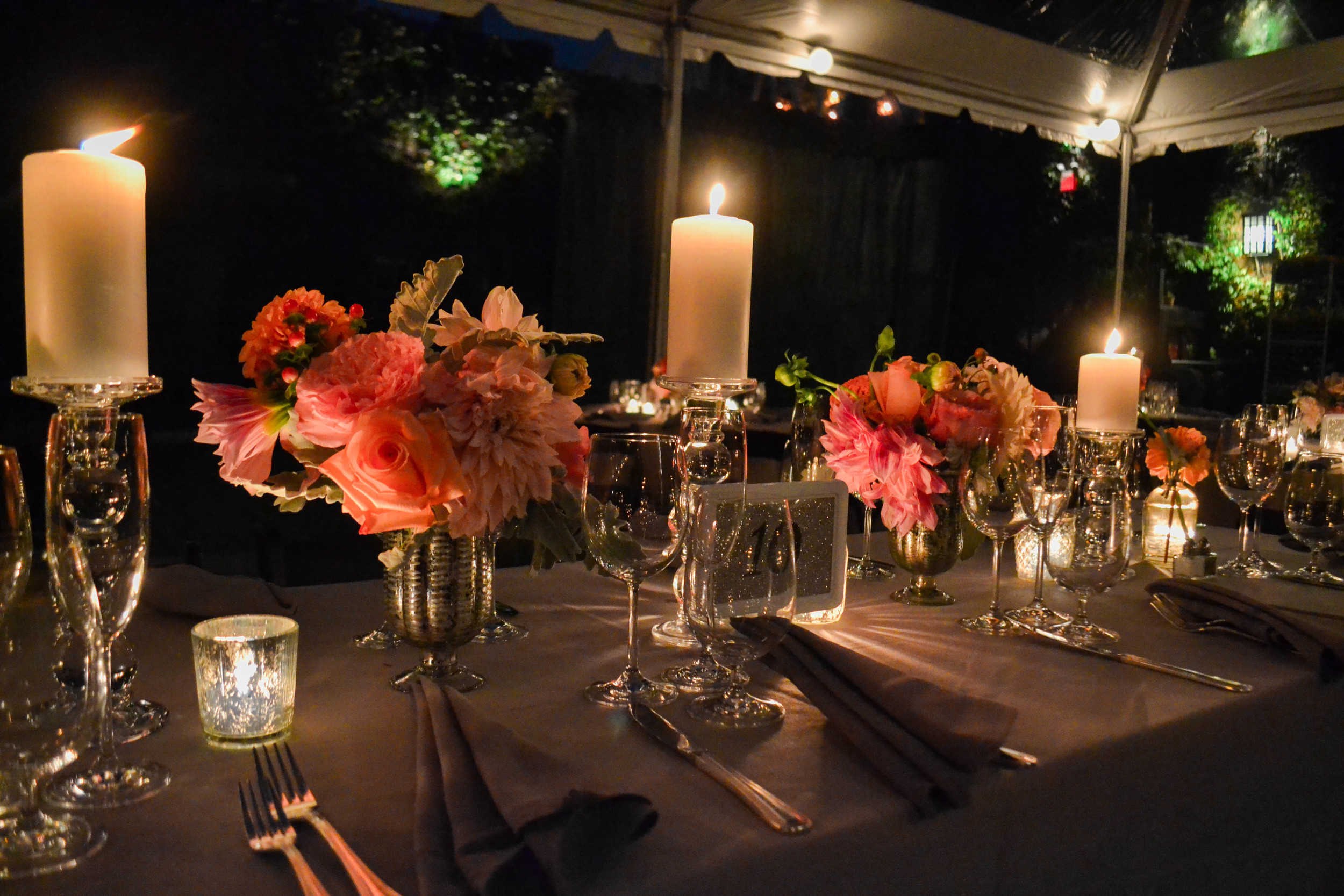 Candlelit centerpieces with pillar candles and pink and peach toned flowers. Foundry LIC. Rosehip Social. 