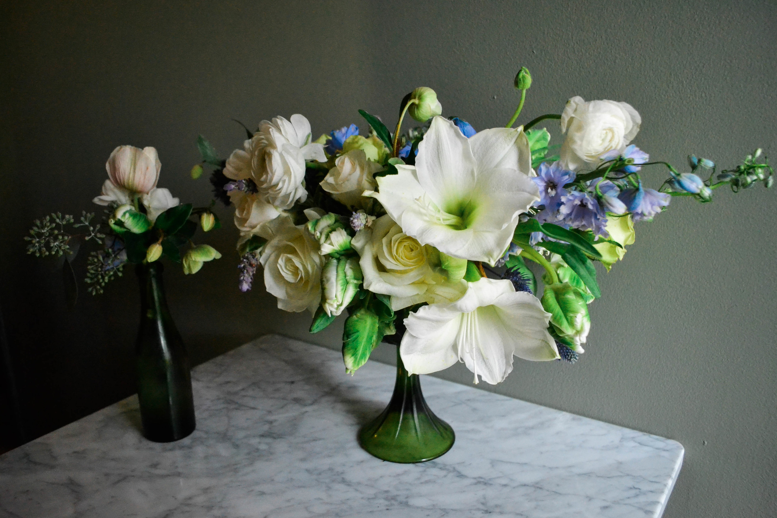 Green and white compote centerpiece flower arrangement with blue and lavender accents. Baby Shower flowers for Garden Collage. Amaryllis, parrot tulip, jade green roses, ranunculous, lavender.