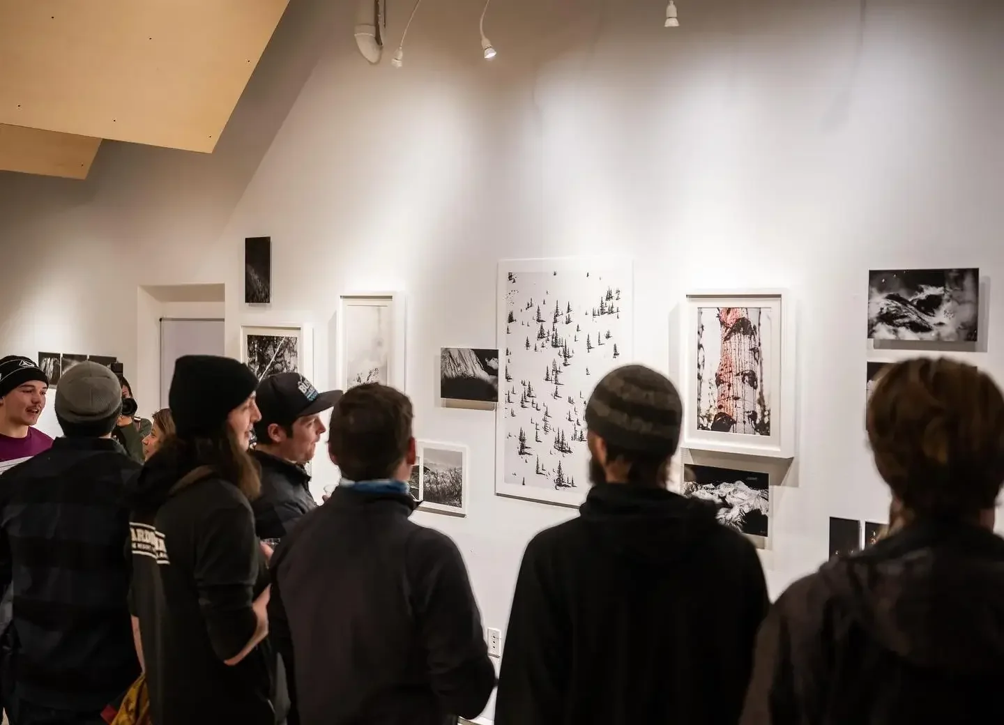 A group of people viewing and discussing photographs at an art gallery exhibition.