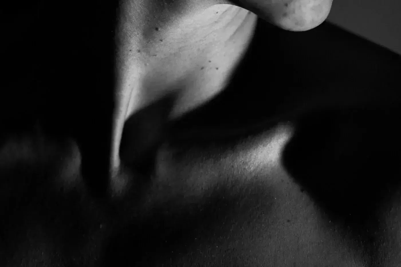 Close-up black and white photo of a person's lips and chin with soft lighting and shadows.