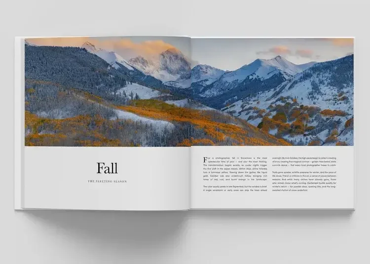 Open magazine showing a landscape of snow-capped mountains and rolling hills with autumn-colored trees, captioned 'Fall The Fleeting Season.'