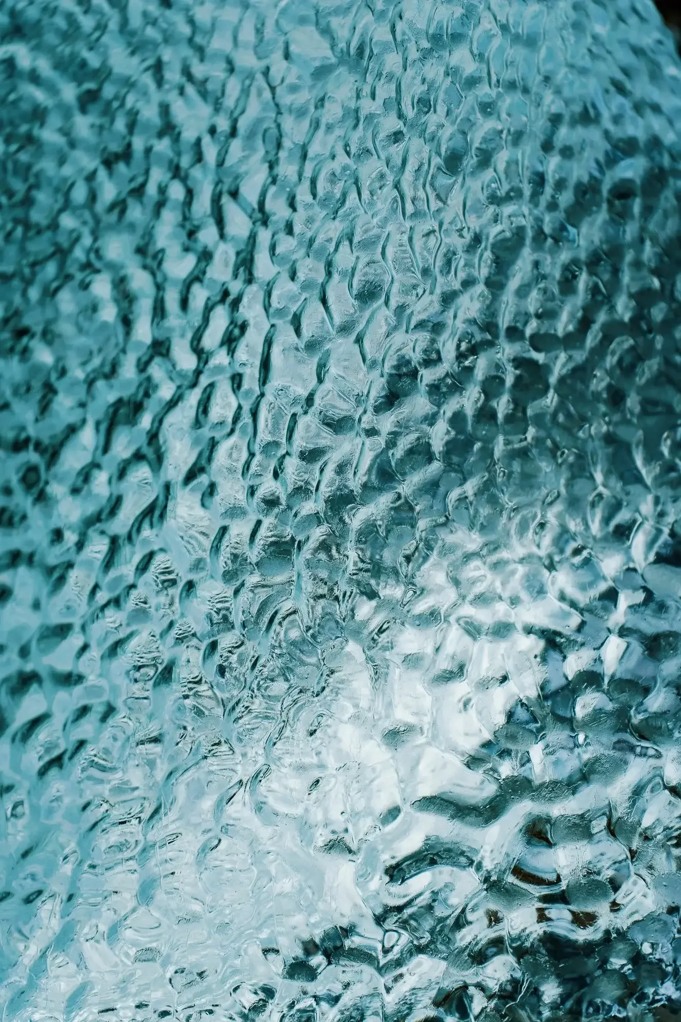 Close-up of a window covered in raindrops or condensation, creating a textured, blurry effect.