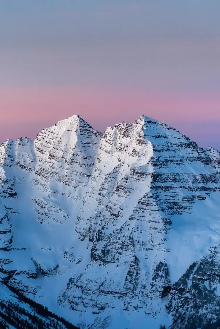 Snow-covered mountain peaks under a pink and blue sky.
