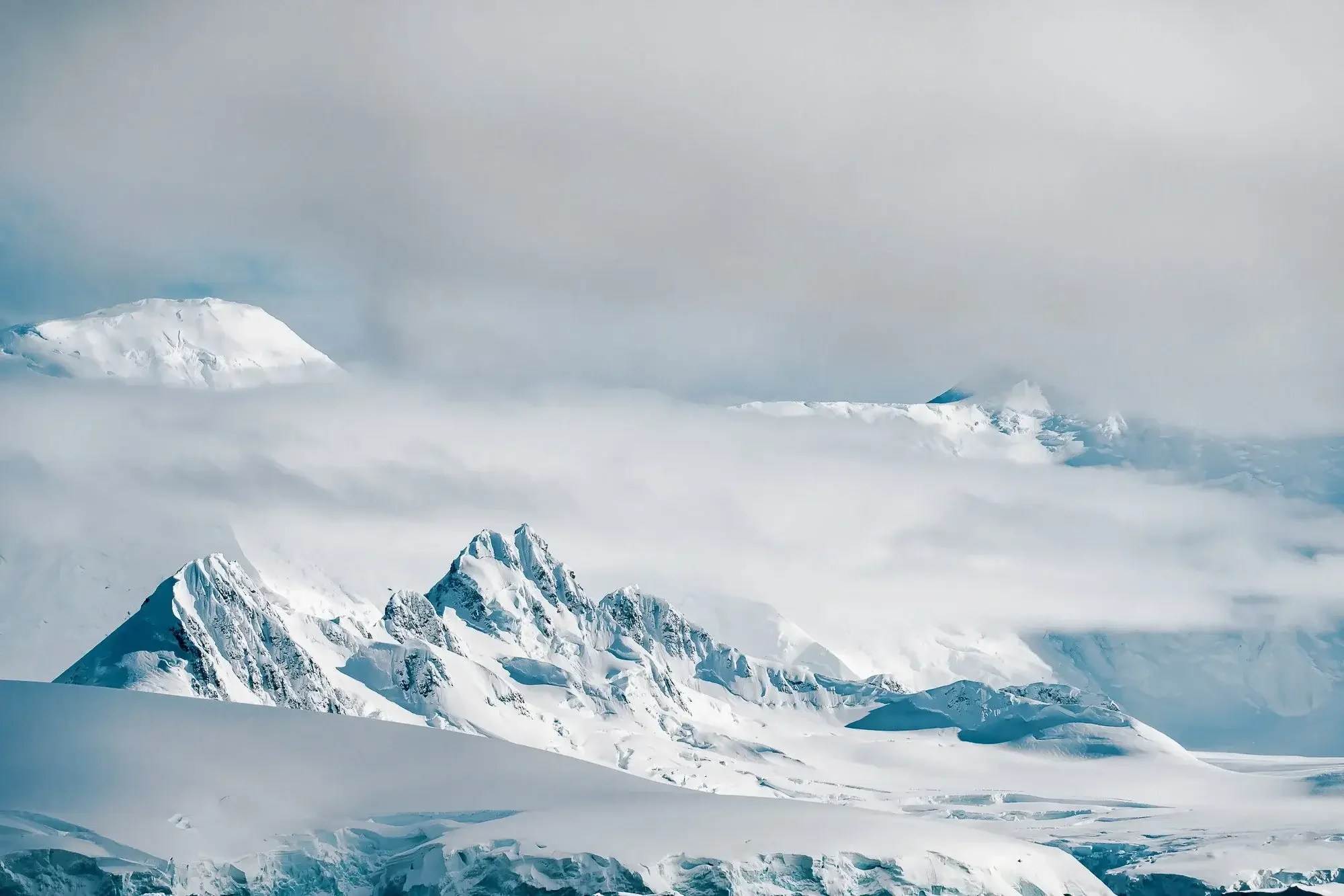 Snow-covered mountains with clouds in the sky.