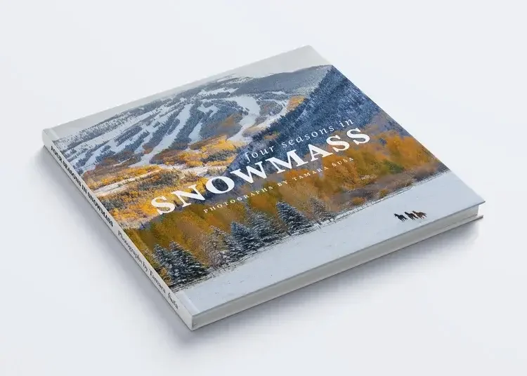 A book titled 'Four Seasons in Snowmass' with a cover image of snow-covered mountains, trees with autumn colors, and a snow-covered field with three horses in the foreground.
