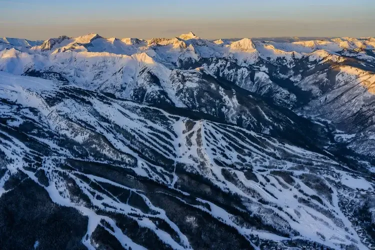 Snow-covered mountain range with ski slopes and trails

