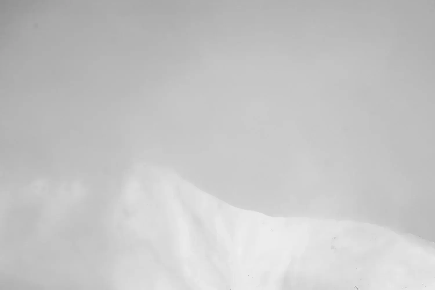 Black and white photo of a river with flowing water around two dark rocks, creating a smooth, blurred effect.
