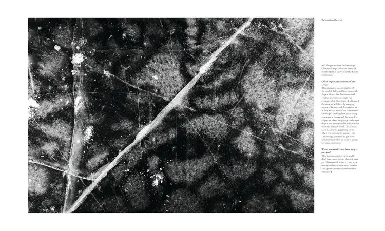 Close-up view of a textured, black and white icy surface with cracks and lines.