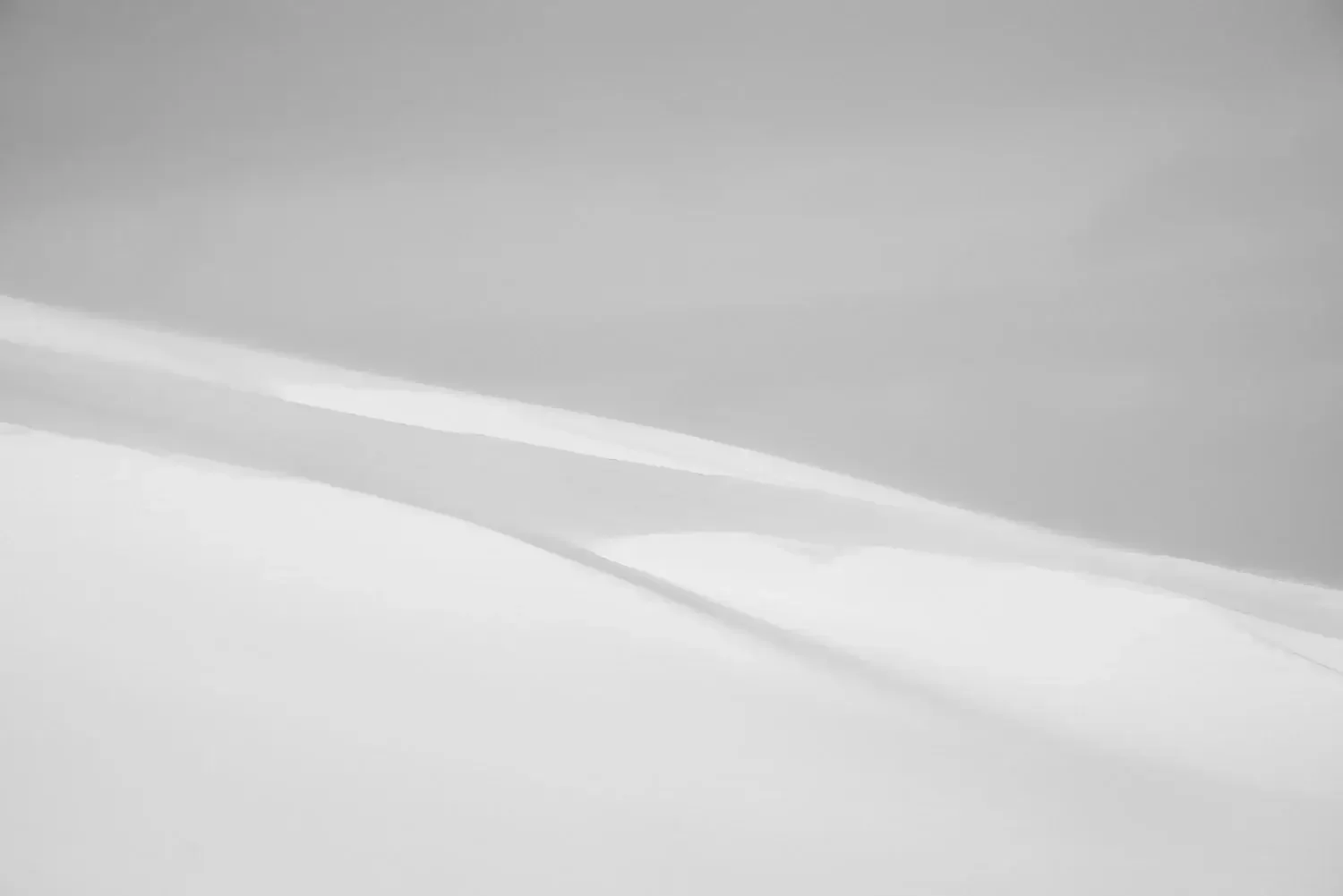 Abstract black and white photo of snow-covered landscape with a snowdrift and dark sky.