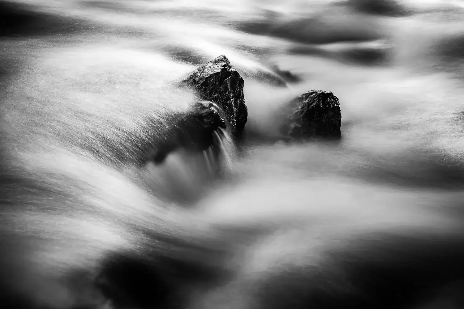 Black and white photograph of snow-covered mountain peaks under a dark sky.
