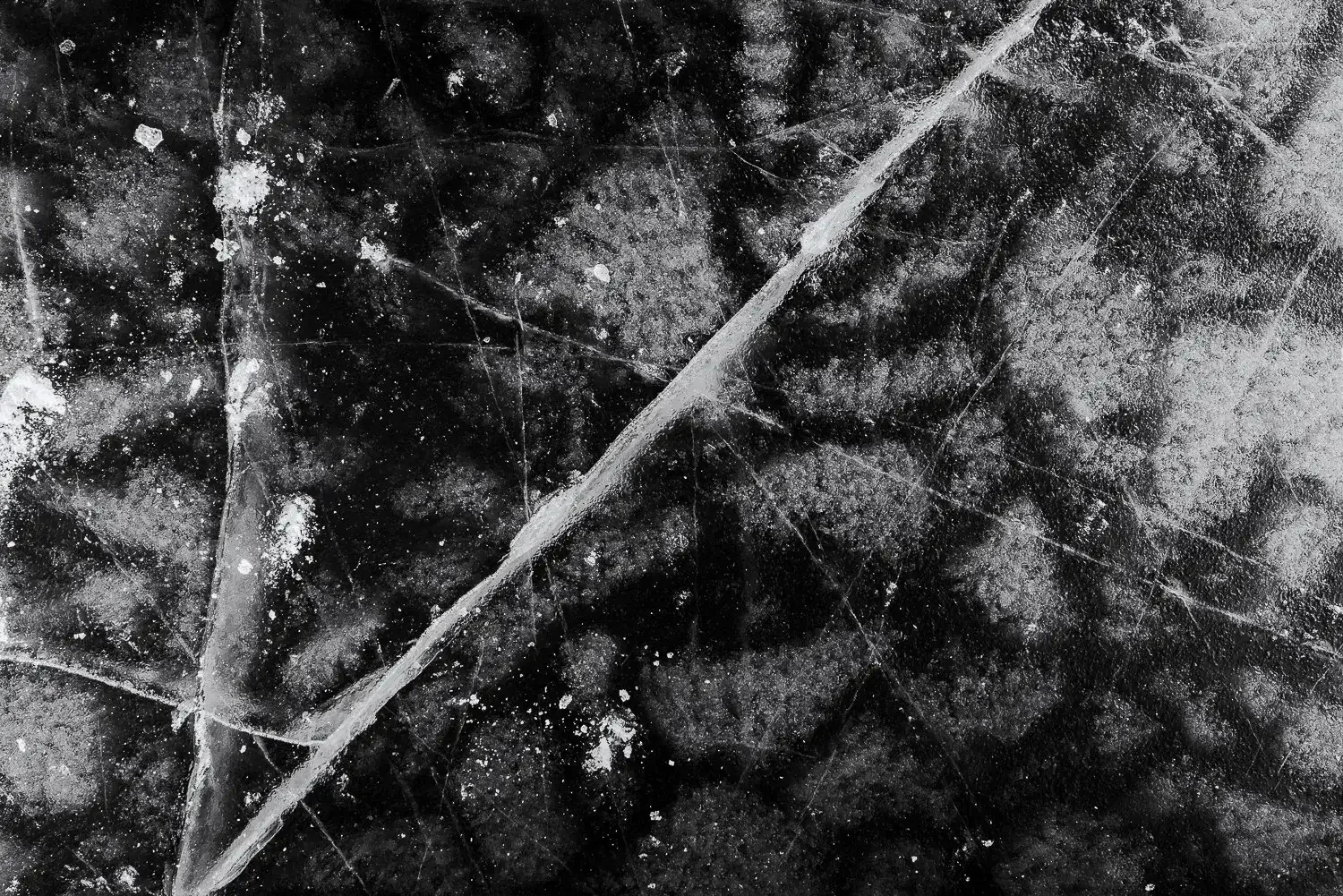 Close-up of a cracked and scratched black ice surface.
