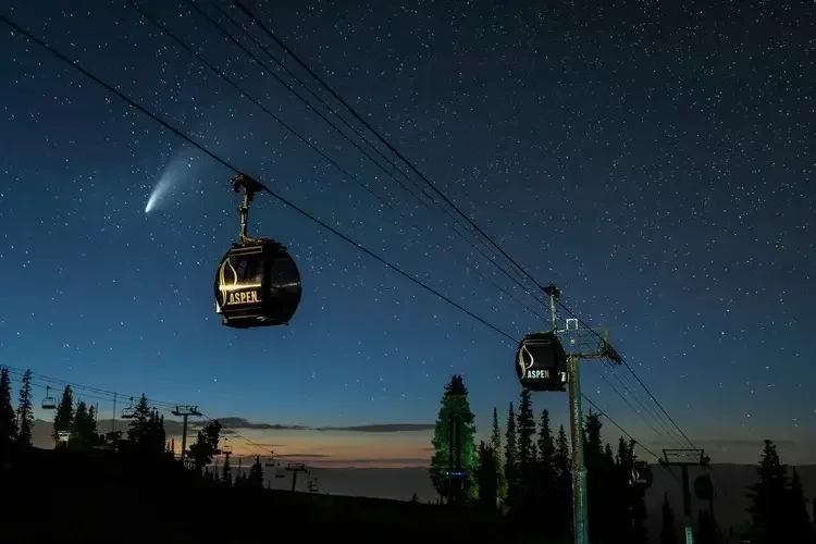 Nighttime scene with starry sky, comet, and ski lift gondolas with 
 