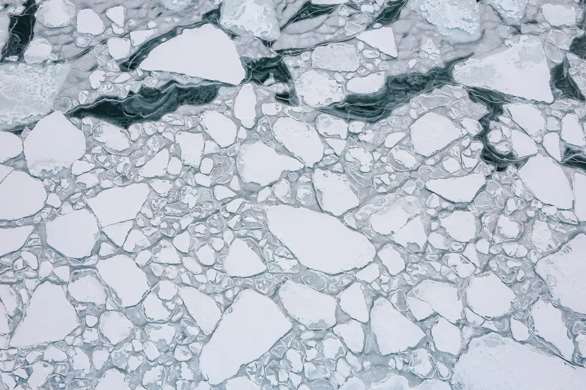 Frozen ice with large and small chunks of white and gray ice, some with dark cracks and streaks.