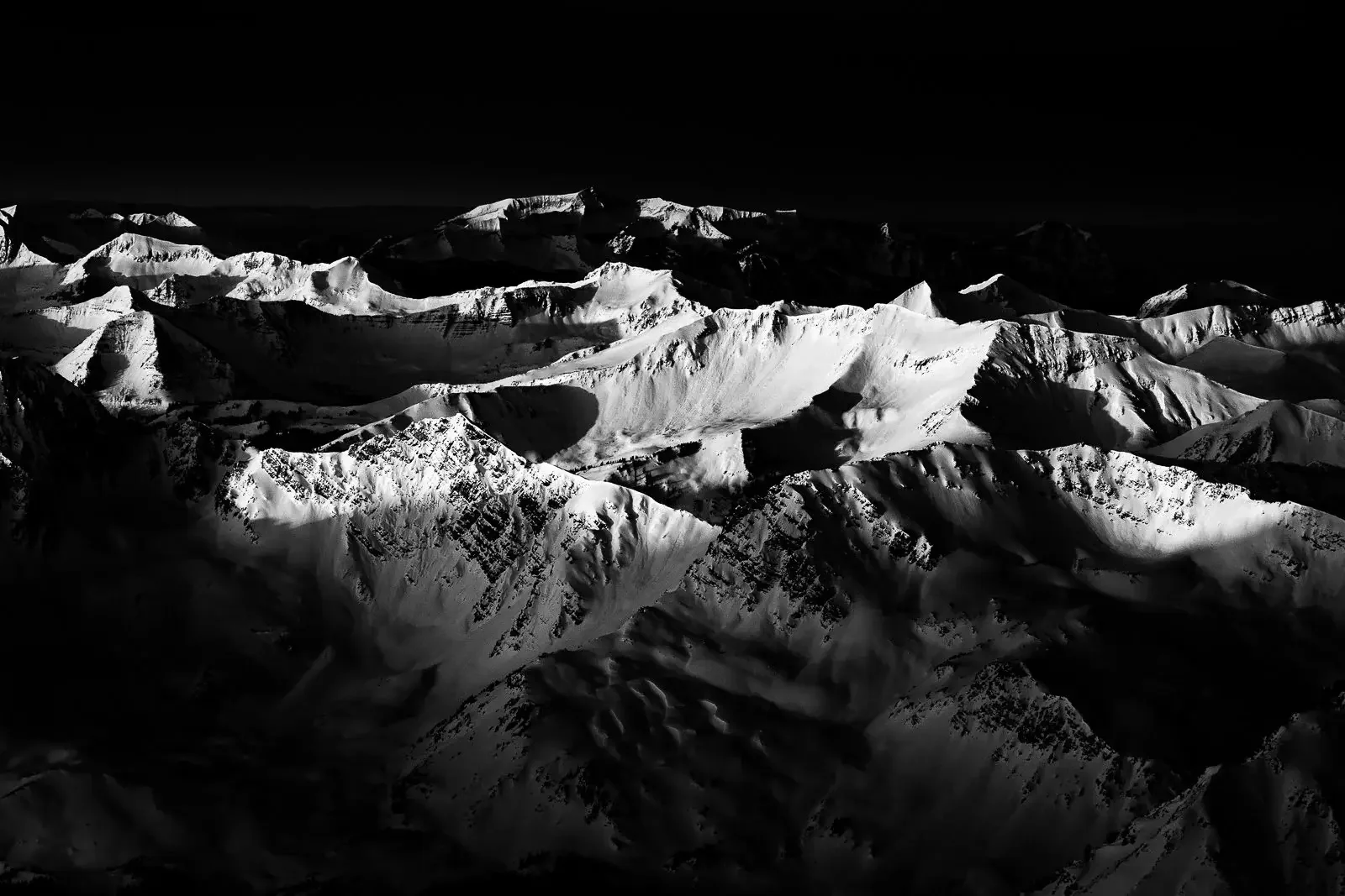 Three black and white landscape photos: a scorched forest with fallen trees, a foggy mountain scene with trees and mist, and close-up of rocks with water flowing over them.
