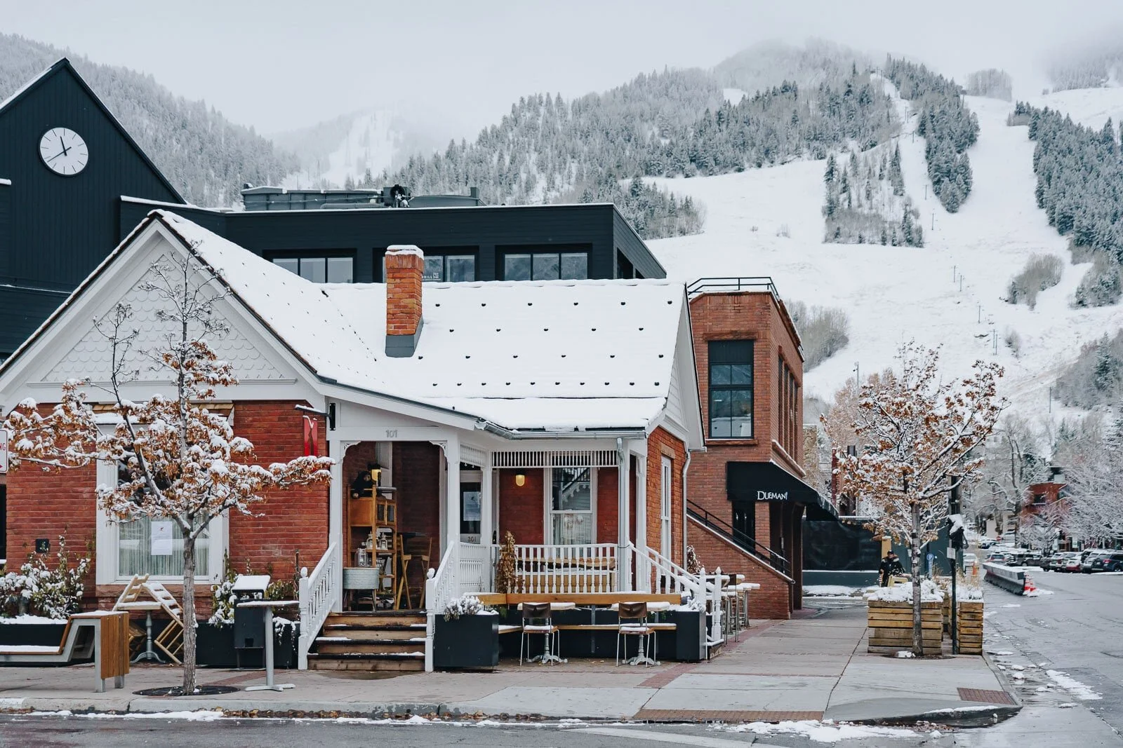Snow-covered buildings and trees in a mountain town street in Aspen during winter.