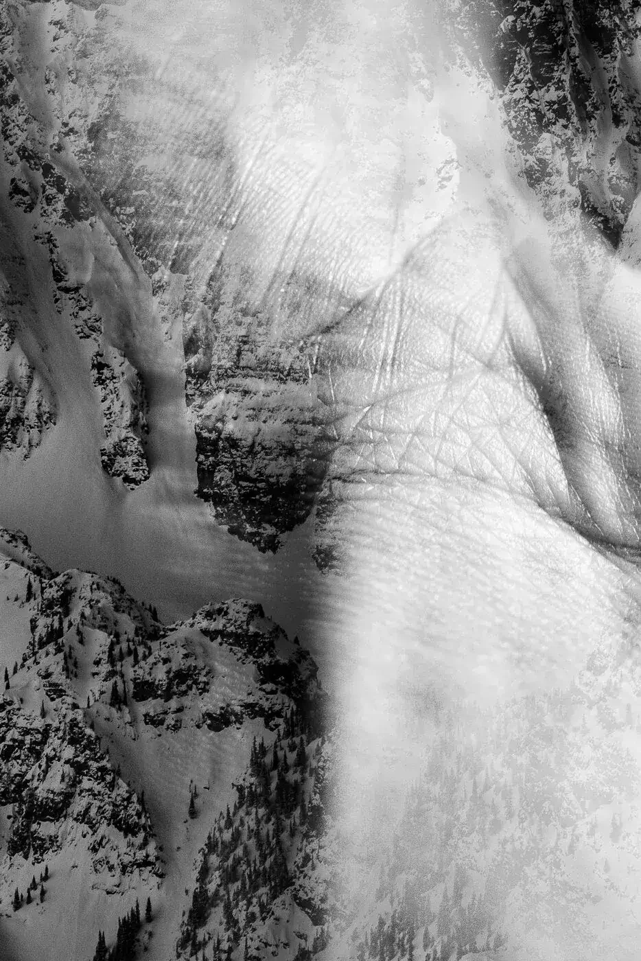 Double exposure black and white photograph of snowy mountain landscape and close-up of a person's face, creating a layered effect.
