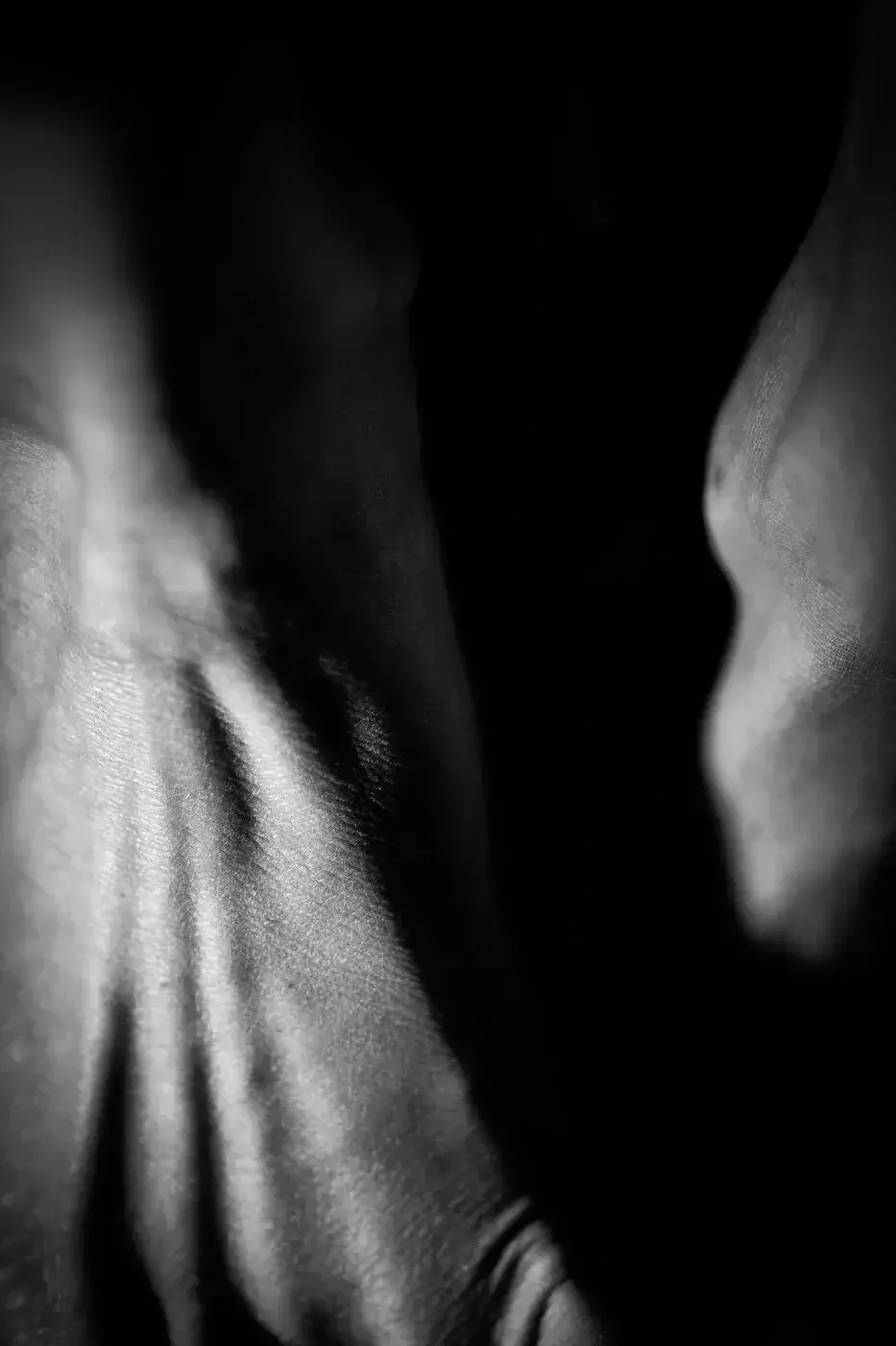 Close-up black and white photograph of human skin, emphasizing texture and contours.