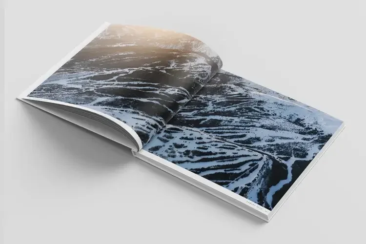 Open book showing a landscape of snow-covered terraced hills during sunset.