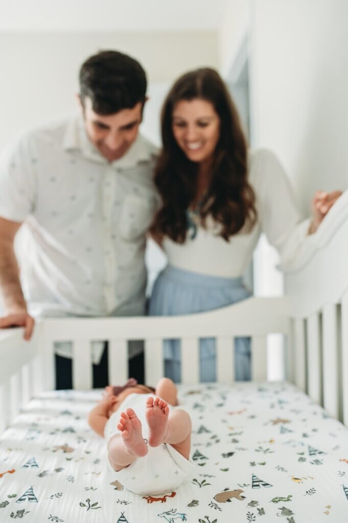 newborn in crib with mom and dad looking on