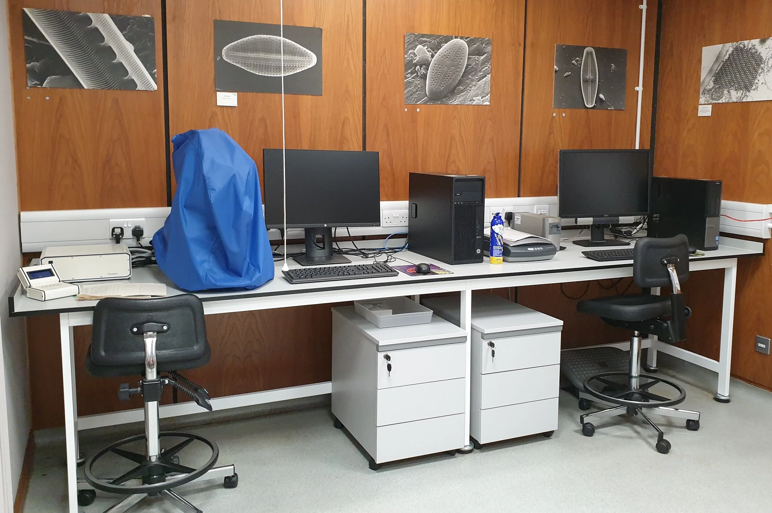 Research desks with grey tops and white table frames with mobile drawer units below.