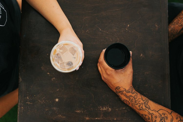 Two people sitting with coffee at a wooden table