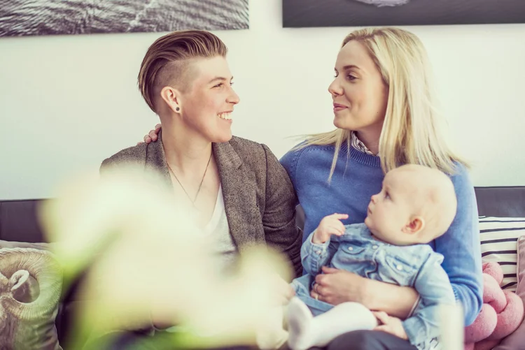 Two women sitting on a couch with their baby