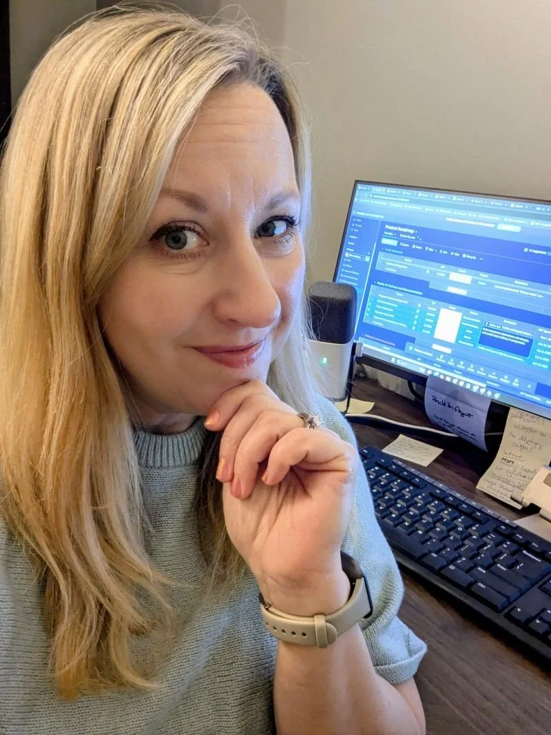 Di Lyngholm at her desk, smiling with her chin resting on her hand