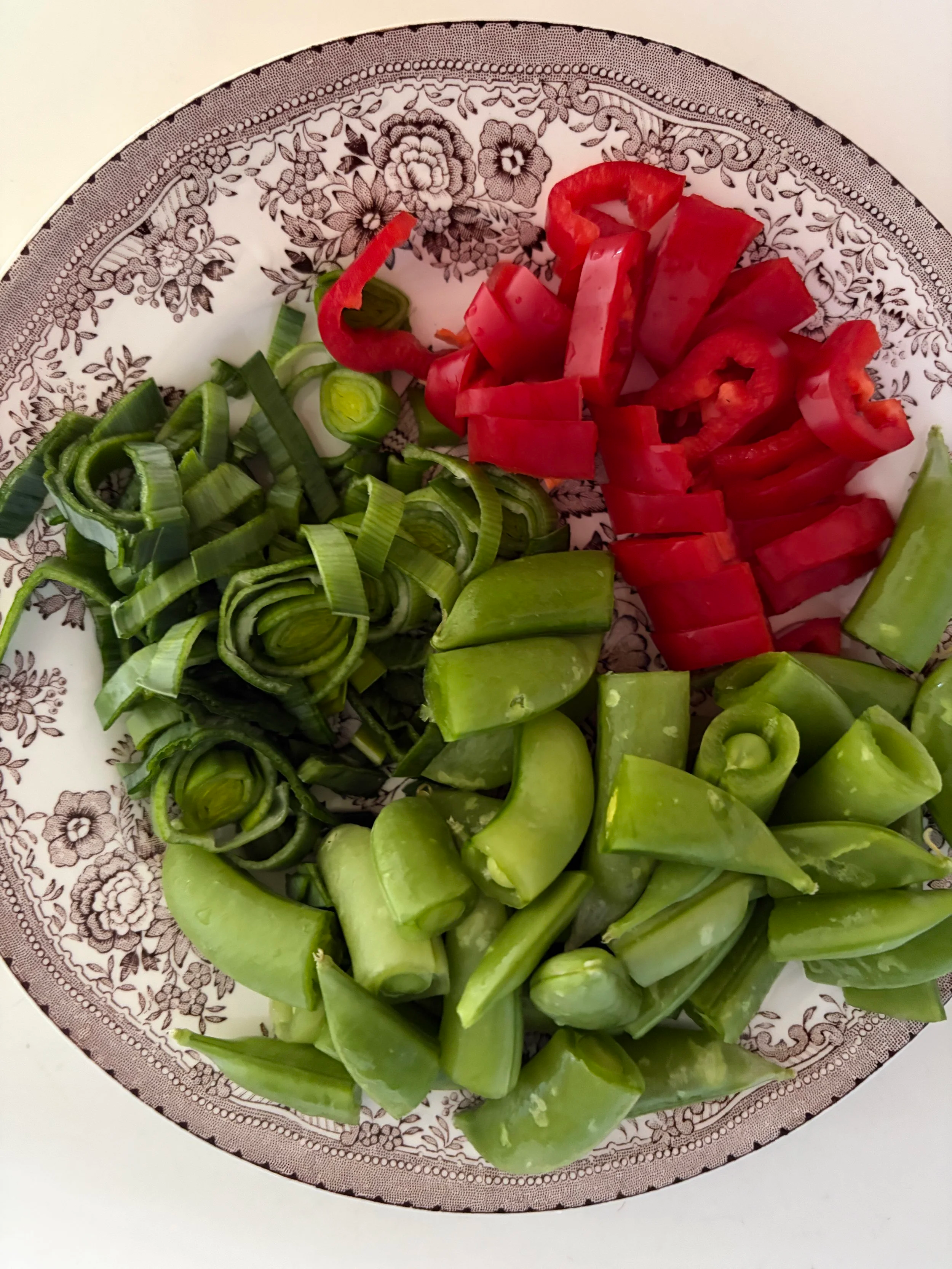 oppkuttet purre, paprika og sukkererter på et fat