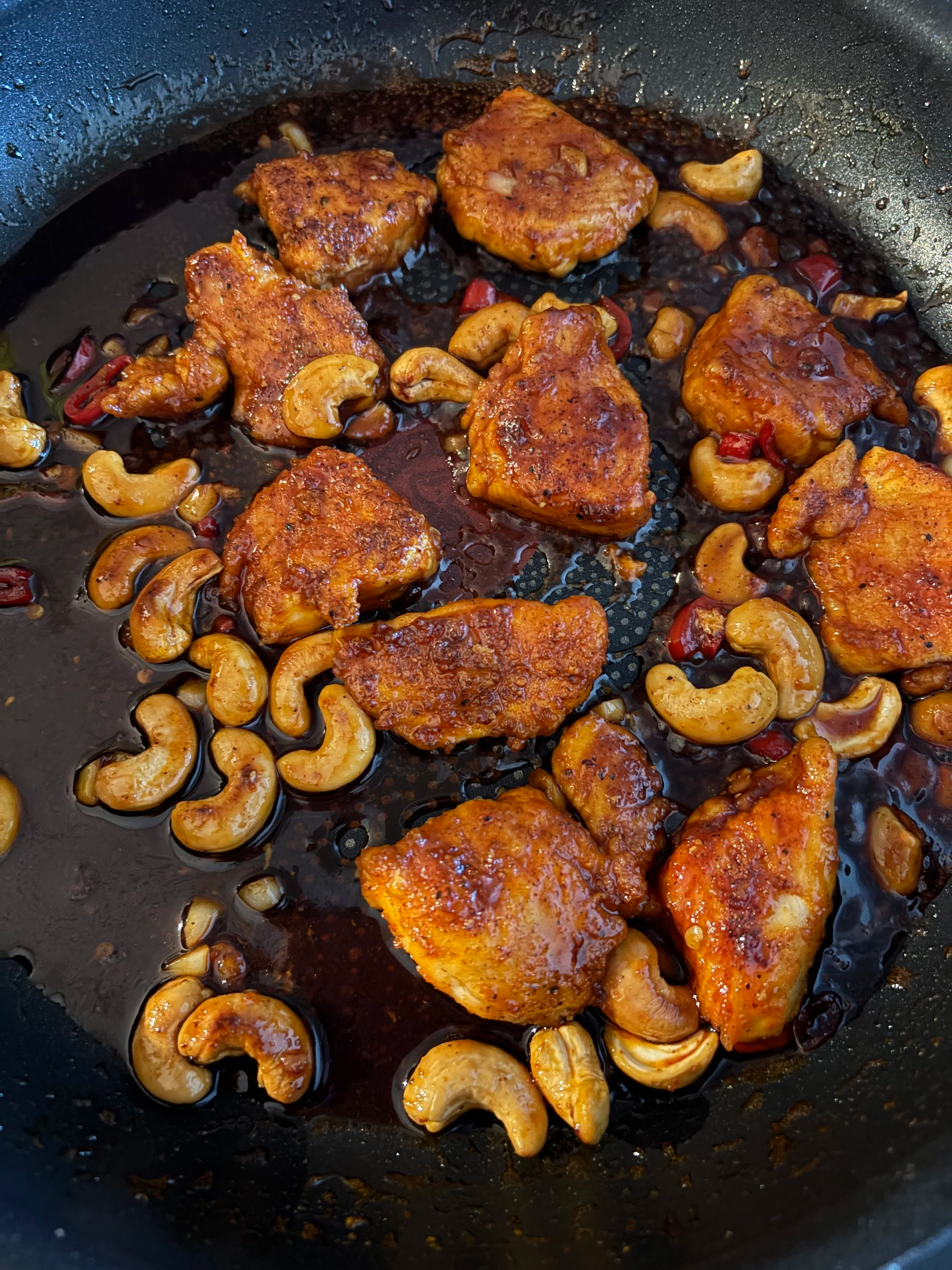 kylling, krydder, nøtter og saus blandet sammen i stekepannen