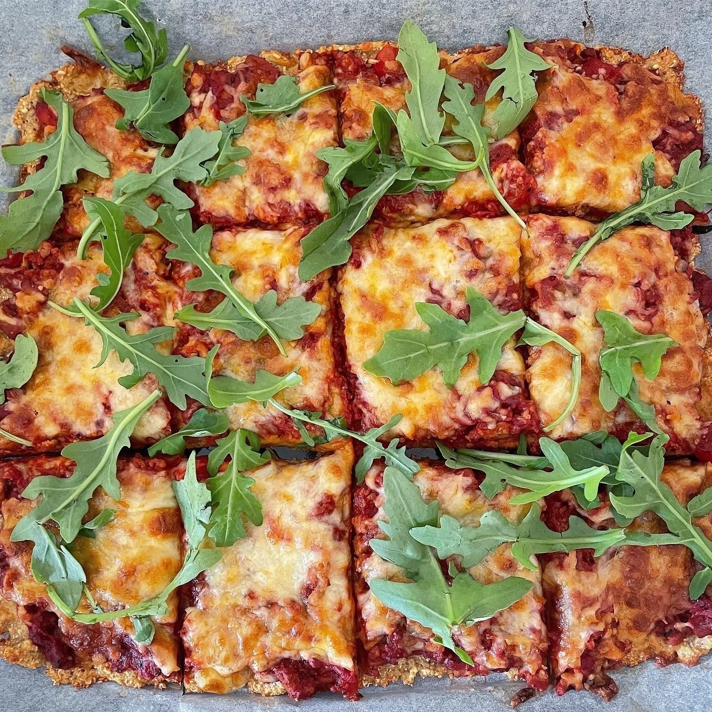 ferdiglaget pizza delt i biter og toppet med fersk ruccola